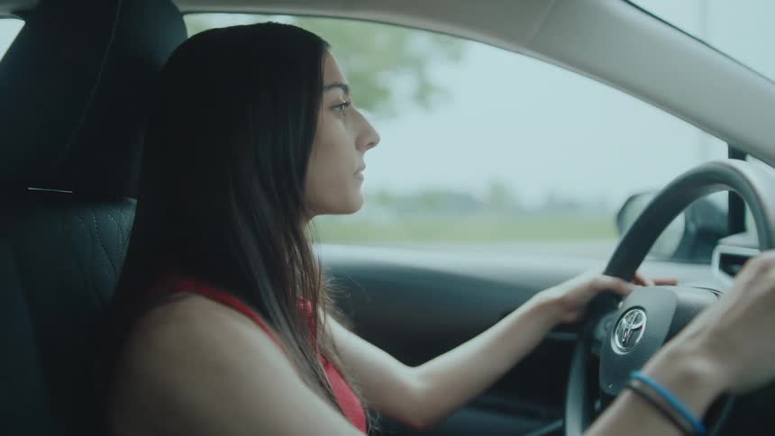 Woman with both hands on the steering wheel and driving in a concentrated manner