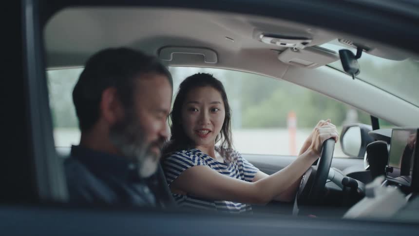 Woman signing a document for driving school instructor while inside the car