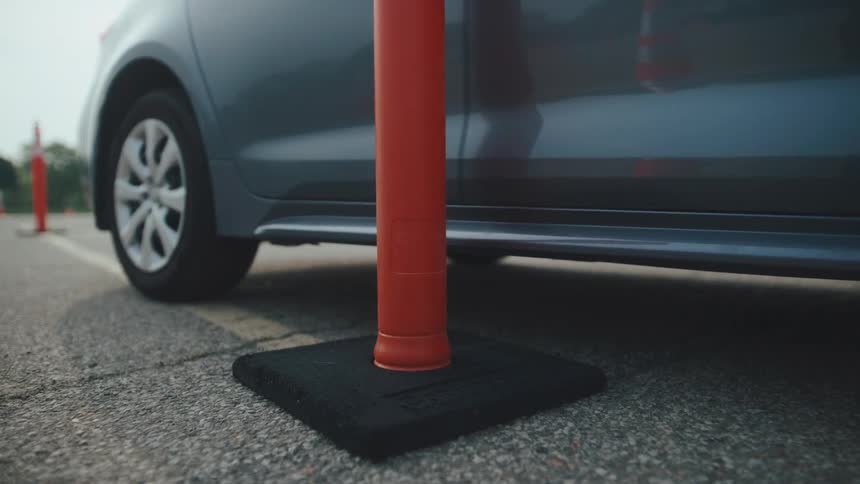 Gray sedan cars driving over a cone