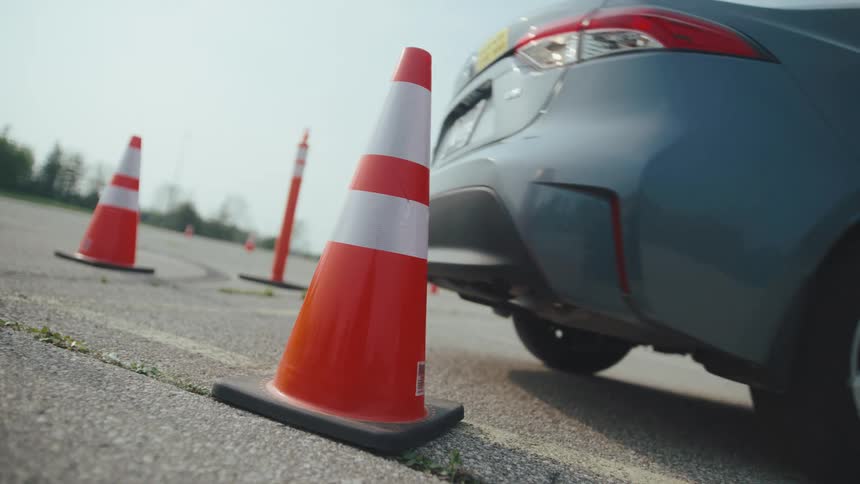The car backs up and hits the traffic cone