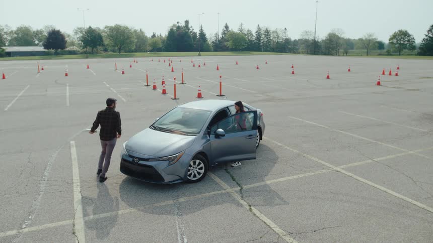 Examiner and a student getting into a car in a yard with cones