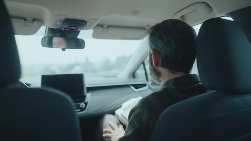 A person driving on a road with a male passenger