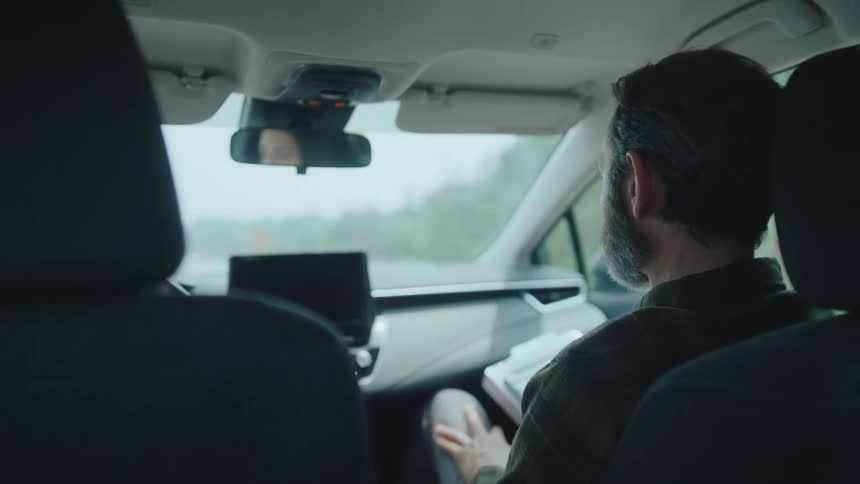 A woman in the drivers seat listens intently while a man beside her reviews something
