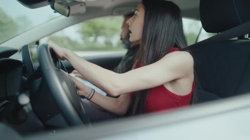 Woman learning to drive accompanied by a man in the car