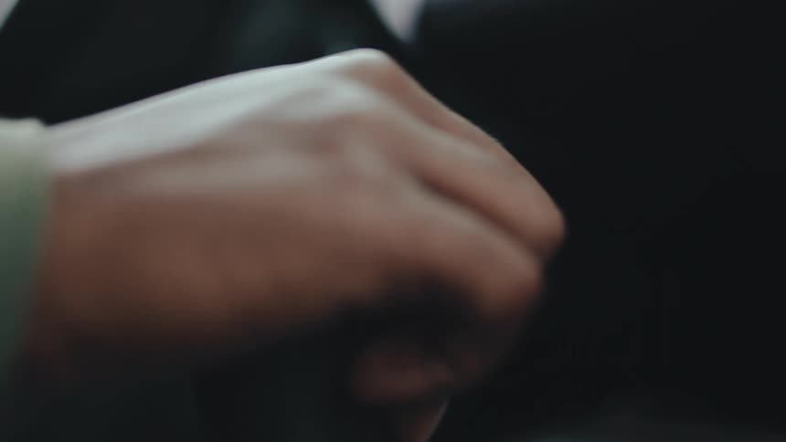 A hand grips a gear shift or control lever in a closeup motion