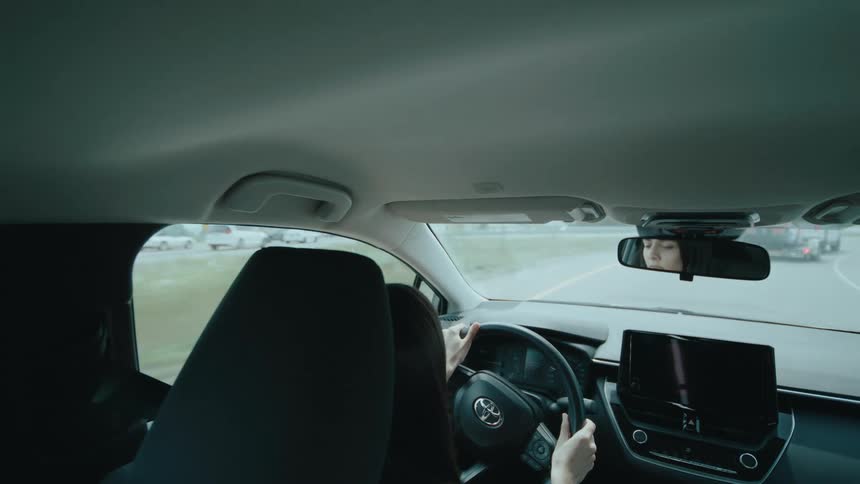 A female is driving in a car on the road
