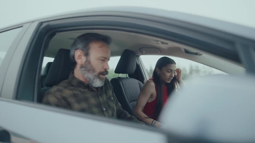 Woman and a man getting into a car and putting on their seatbelts