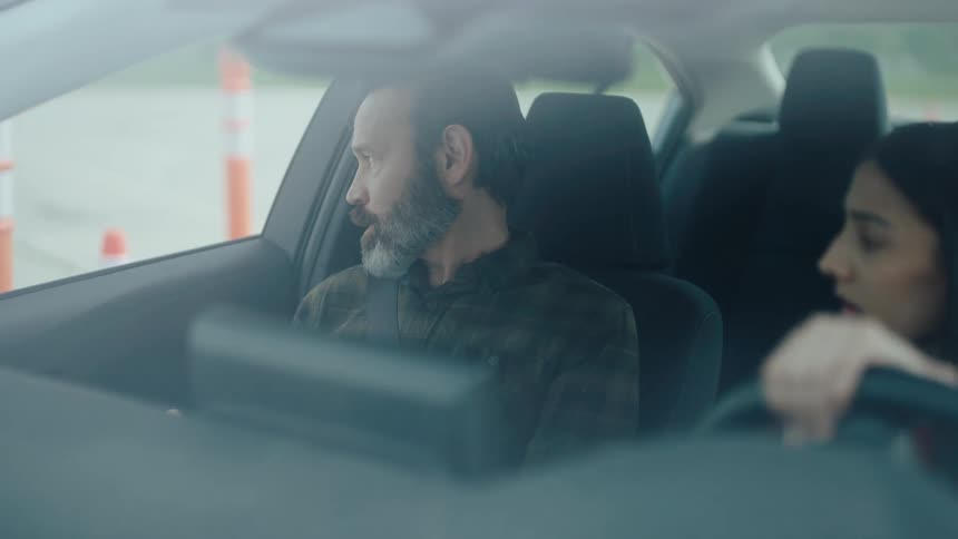 Examiner inside the car with a woman accompanying her to perform a parking