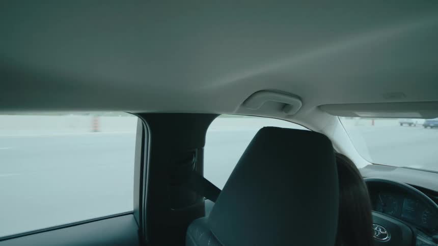 A woman drives on the highway as traffic passes by