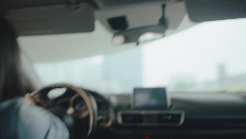 A woman turns the steering wheel while driving a car