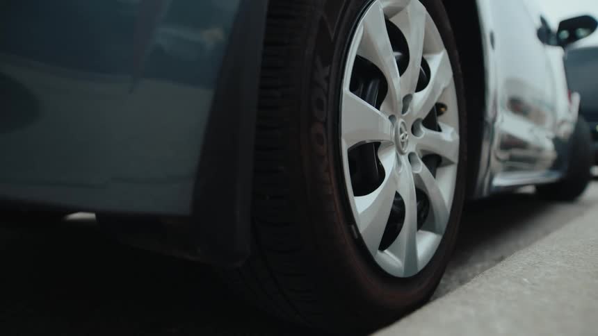 Gray sedan car reversing and parking in a parking space on the street