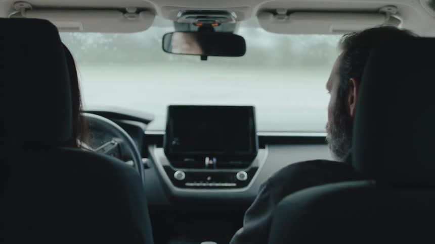 Close up of a young asian woman practising driving with a male instructor in a vehicle during daytime