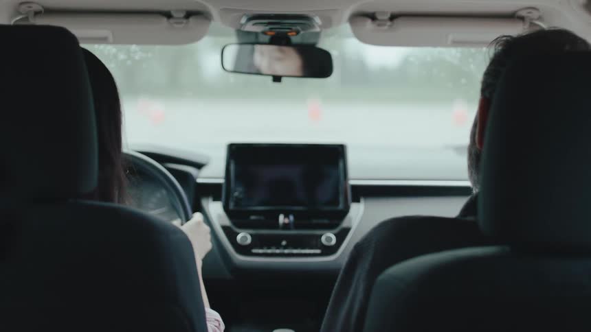 A woman is driving while a passenger sits beside her in a car