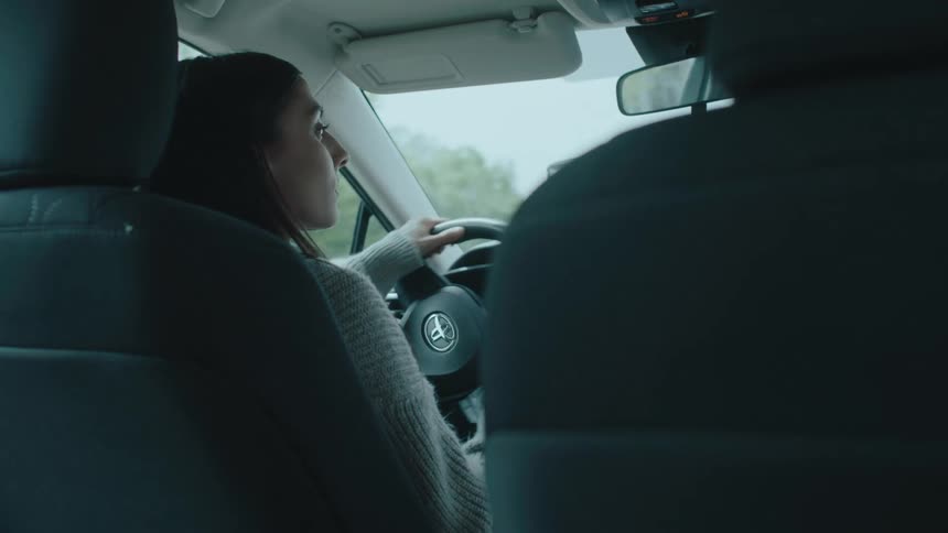 The girl is turning the steering wheel in the car