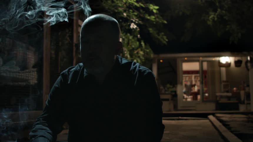 A man smokes outside in the dark