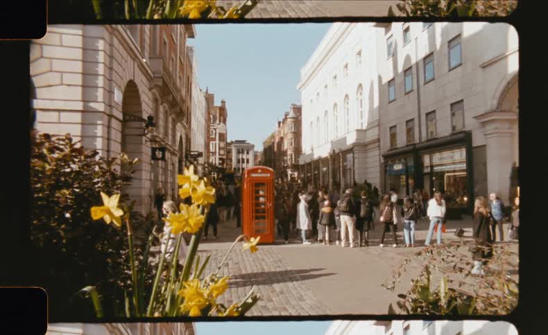 Busy street with people walking past a red phone booth in a historic city