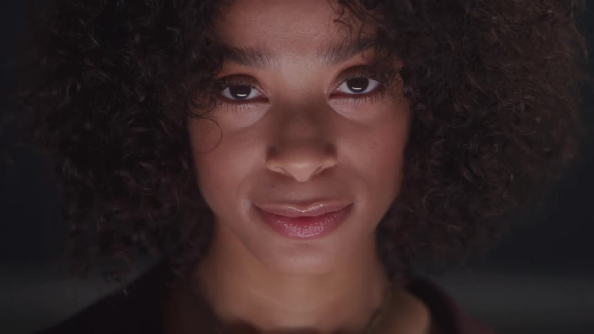 Close up portrait of a young black woman standing in a dark studio