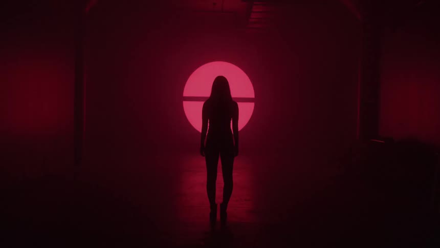 Silhouette of a woman in a dark room with symbols appearing on a wall