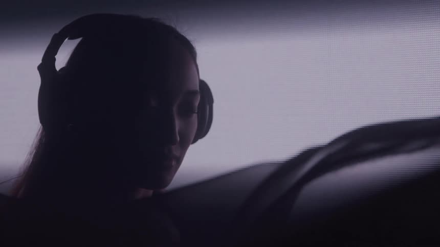 A black veil moves in front of the woman wearing headphones