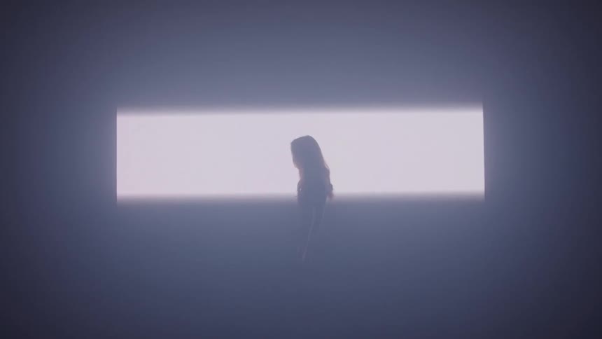 The light slowly spreads on the wall where the woman is standing