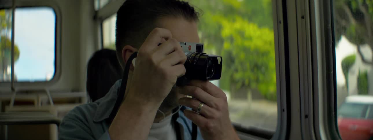 A man takes a photograph sitting in a bus