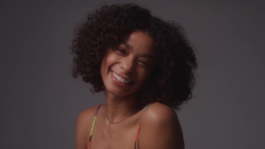 A model poses and smiles and brushes her hair