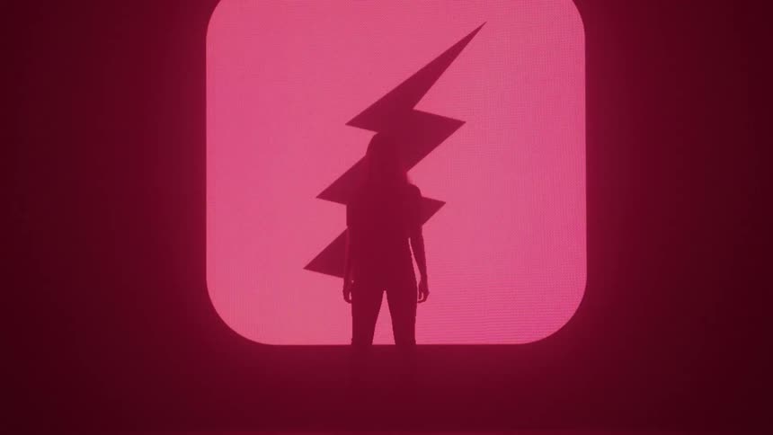A silhouetted figure stands in front of a glowing red radiation symbol that flickers and disappears into darkness