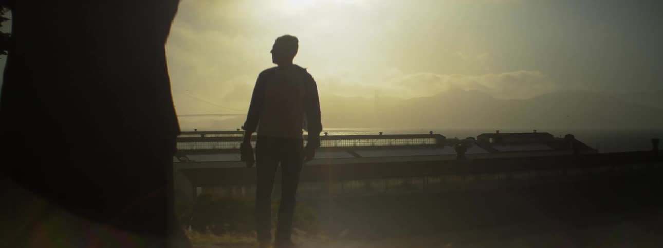 A man stands outdoors on a breezy and sunny day