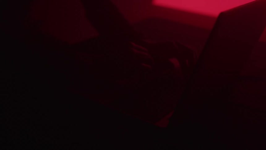 Woman types on a laptop while the lighting changes from red to blue in turn