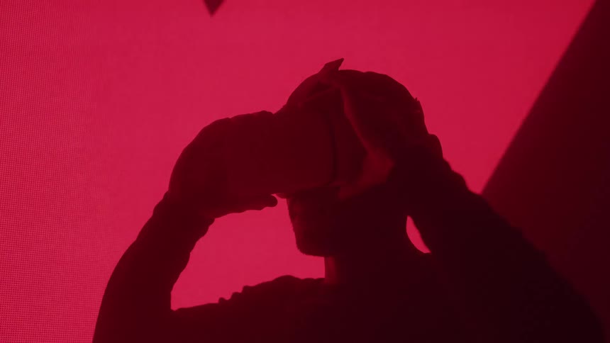 Red light flashes fast as the man puts on a virtual reality headset