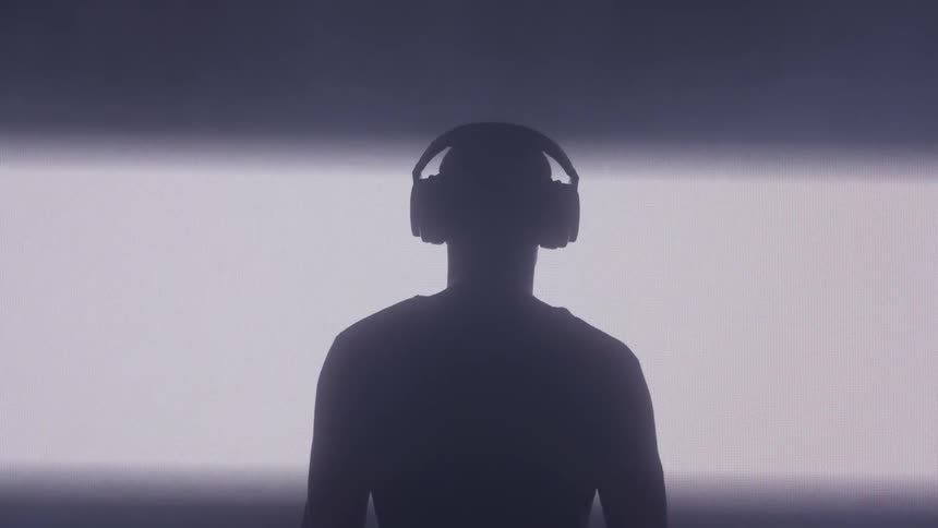 A man puts on his headphones as the room lights up