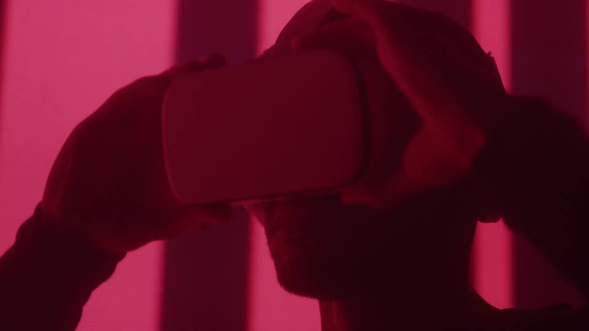 A person wears a virtual reality headset silhouetted against vivid red lighting
