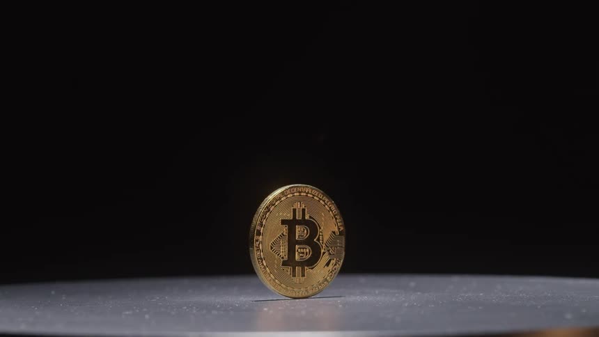 A single coin with the bitcoin logo imprinted on it is stood on its side