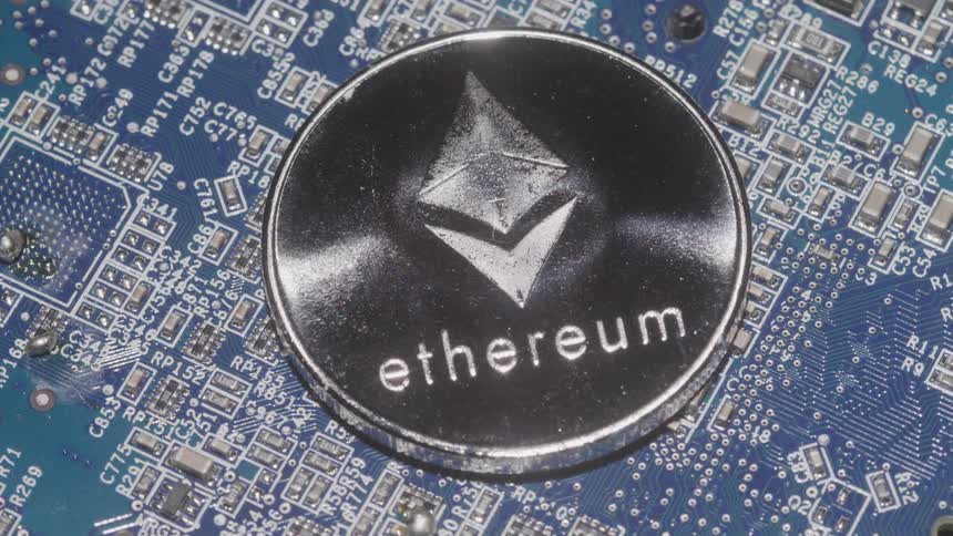 A closeup reveals a golden ethereum coin positioned upright on a circuit board symbolizing the intersection of digital currency and technology the coins intricate details are highlighted against the blurred green and blue elements