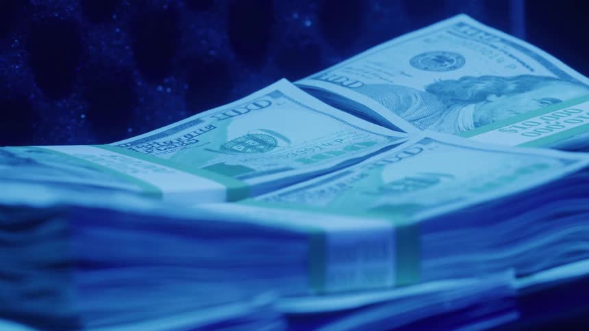 Close up of a cash currency bundles on a surface in a blue lit room