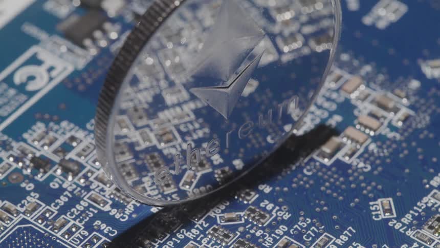 A reflective silver coin with writing on it sits on top of blue a circuit board
