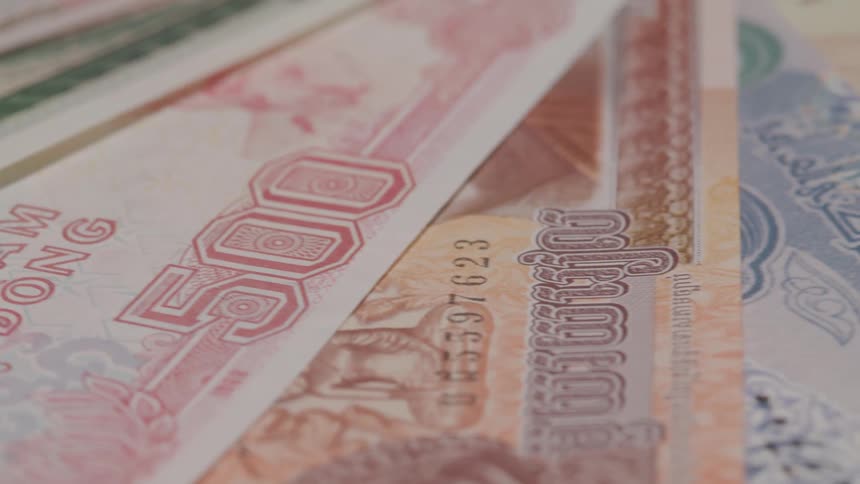 A collection of colorful international currency is spread out revealing the unique designs and scripts from various countries