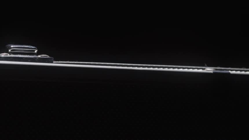 A long narrow strip of white light emerges from darkness and extends across the frame with smaller individual lights visible along its length the stark contrast between the bright light and dark background creates a clean modern aesthetic