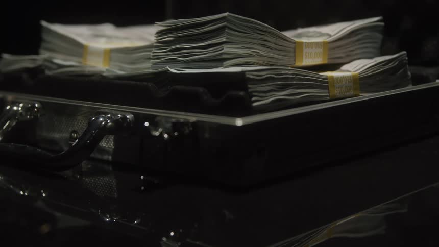 An open briefcase has stacks of paper currency piled within it