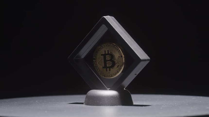 A single coin with a bitcoin logo on it is displayed in a holder