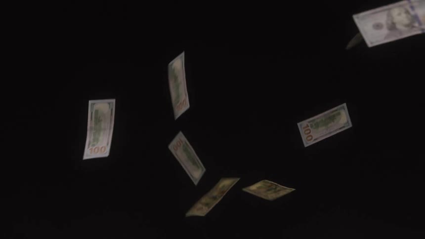 Money floats as it falls in the dark room
