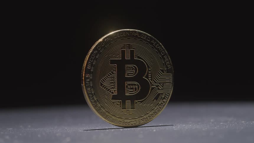 A gold coin stands upright with the letter b inscribed on it representing bitcoin a digital cryptocurrency