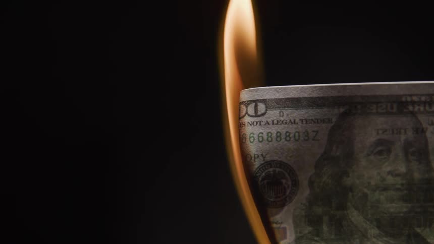 Close up of a paper currency burning in a dark room