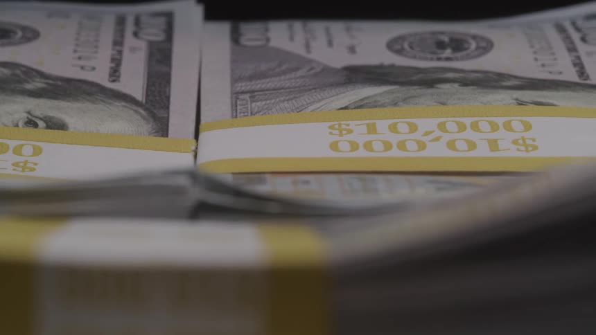 A closeup shot reveals multiple stacks of one hundred dollar bills each held together by a tenthousanddollar currency band