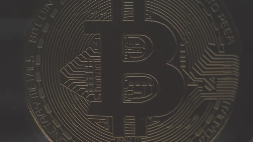 Close up of a physical bitcoin currency placed vertically in a rotating diamond structure