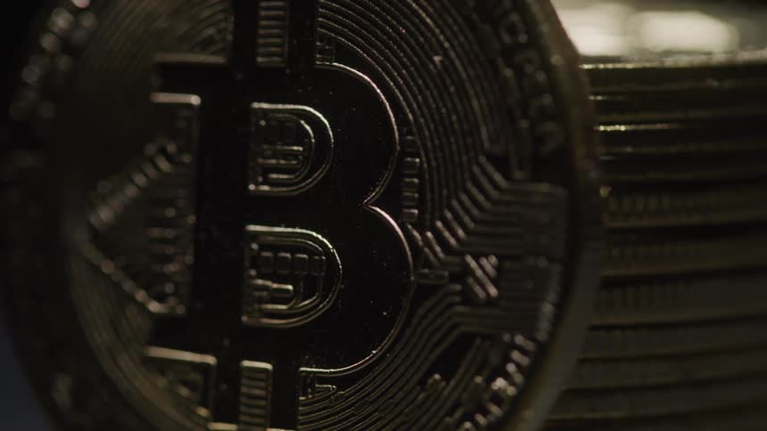 A closeup of a shiny physical bitcoin coin reveals intricate circuitry details