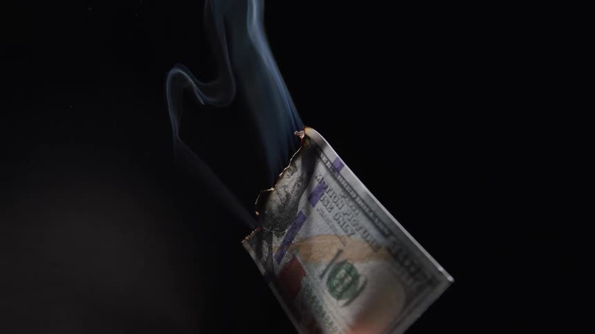 Hundred dollar bills burning against a black background