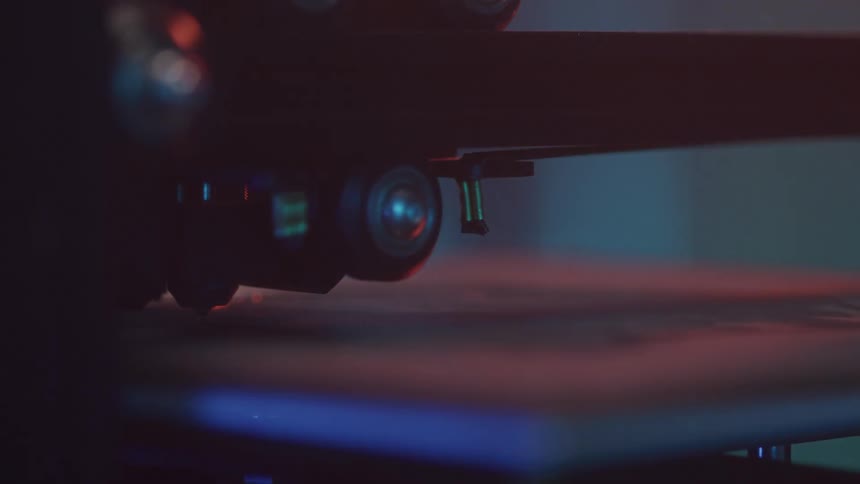 A detailed closeup of a 3d printer in operation specifically focusing on its nozzle as it precisely moves across the print bed extruding material to build an object layer by layer the scene is dimly lit highlighting the intricate mechanical movements