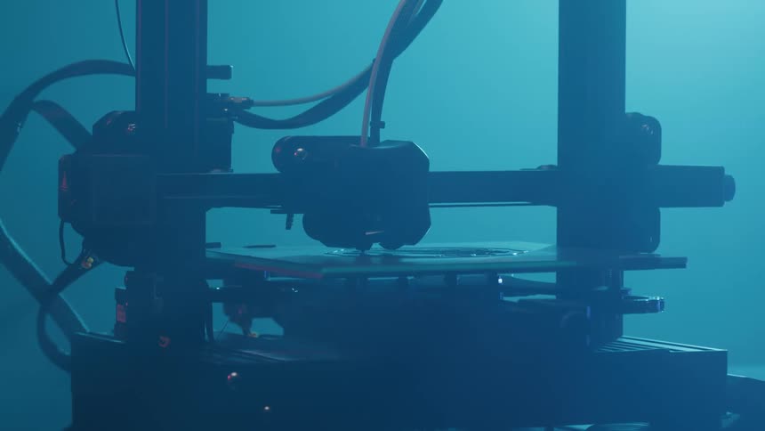 A 3d printer head moves back and forth as prints on a flat surface