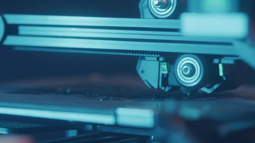 A closeup shows the heated tip of a 3d printer or similar machine